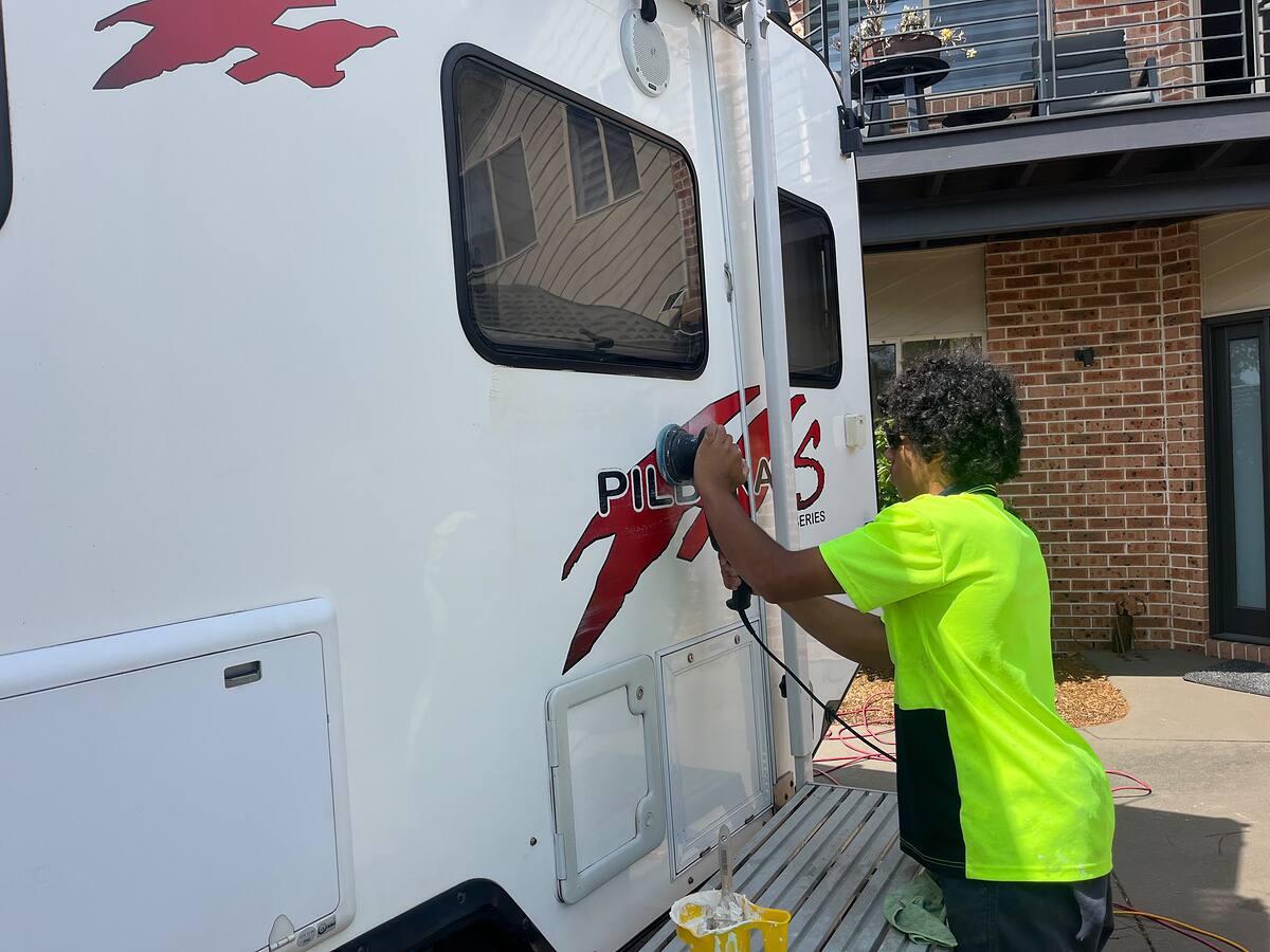 Machine polishing the side of a caravan at the owner's home
